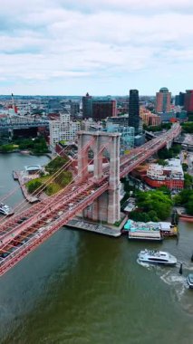 Üzerinde Amerikan bayrağı olan New York 'taki Brooklyn Köprüsü' nün desteğine yaklaşıyoruz. Köprüden çok sayıda insan ve araba geçiyor. Dikey video.
