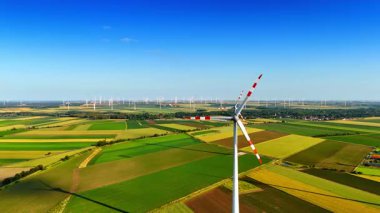 Yel değirmeninin dönen bıçaklarına yaklaşıyoruz. Yeşil enerji üreten rüzgar tarlalarına hava perspektifi.