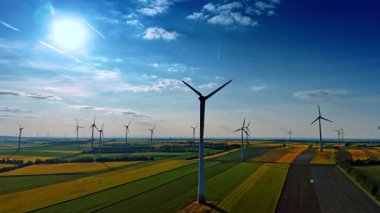 Birden fazla yel değirmeni sahada dönüyor. Sürdürülebilir enerji kaynakları ve yaşam tarzı. Hava görünümü.
