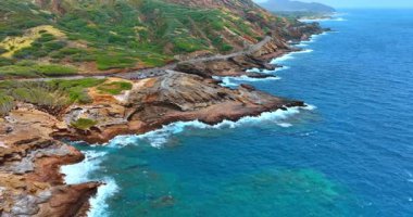 Dalgaların gücüyle kıvrılmış kayalık bir kıyıdan uzakta. Oahu 'nun resimli sahili, Hawaii, ABD.