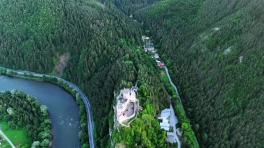 Dağın tepesinde nehrin üzerinde ayaklarından akan güzel bir kale. Yeşil ağaçlarla kaplı Tatra Dağları üzerindeki insansız hava aracı görüntüleri. Slovakya.