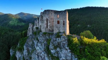 Tepesinde kale olan yüksek bir kaya. Manzara etrafında insansız hava aracı görüntüleri. Arkaplanda çarpıcı yeşil dağlar.