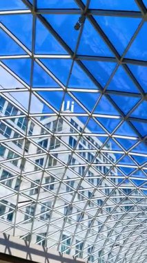 Mavi gökyüzü olan modern cam mimarisi. Cam ve çeliğin eşsiz geometrik yapısı çağdaş bir binanın üzerinde parlak mavi bir gökyüzü sergiliyor..