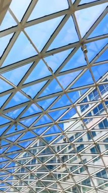 Şehir ortamında cam tavan yapısı. Modern cam tavan, açık mavi gökyüzüne karşı karmaşık geometri içerir, mimari güzelliği sergiler..