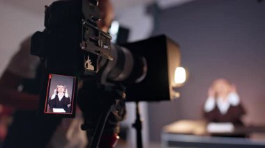 Modern kameranın önünde Esmer Kafkas kadın. Kapatın. Tanımlanamayan bir kadın kameranın yanında durup ekipmanları tamir ediyor. Bulanık arkaplan.