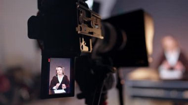 Beyaz bir kadın modern kameranın önünde blog kaydediyor. Kapatın. Bir videonun stüdyo görüntüleri.