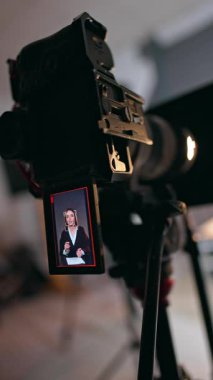 Modern bir kamera beyaz bir bayanı tasvir ediyor. Kapatın. Blogcu konuşur ve ellerini sallar. Dikey video.