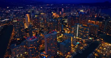 Geceleri modern, canlı şehrin göz kamaştırıcı manzarası üzerinde uçmak. İnsansız hava aracı görüntüleri Honolulu, Hawaii, ABD 'deki Waikiki tatil beldesinin üzerinde..