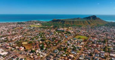 Alçak katlı yerleşim alanlarıyla çevrili Diamond Head Krateri 'ne yaklaşıyoruz. Pasifik Okyanusu 'nun gök mavisi su manzarası. Hava görünümü.