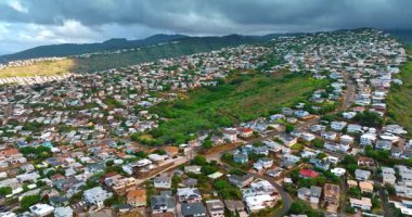 Dağların yamaçlarını kaplayan alçak binalar. Arka planda gökyüzünde dramatik bulut manzarası. Honolulu, Hawaii, ABD.