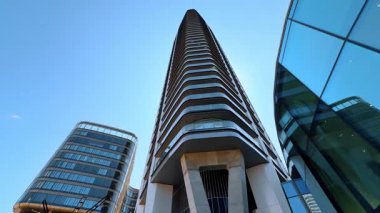 Şehirdeki ya da şehirdeki modern binaların dışındakiler. Mavi gökyüzünün arkaplanındaki mimari tasarımda alçak açı görünümü.