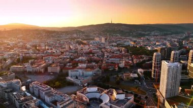 Batan güneş, turuncu çatıları olan eski şehrin manzarasını kamaştırıyor. Dağ silueti arka planda. Bratislava şehri, Slovakya. Hava görünümü.