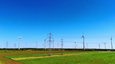 Ülkede elektrik hatları ve rüzgar türbinleri olan geniş alanlar. Arka planda inanılmaz açık mavi gökyüzü.