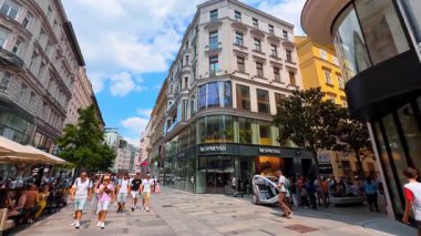 Viyana, Avusturya - 9 Haziran 2025: Güneşli Wien 'de turistler. Turistler, açık bir gökyüzü altında alışveriş ve yemek yaparak Avusturya 'nın Wien kentinin canlı sokaklarını keşfediyorlar..