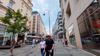 Viyana, Avusturya - 9 Haziran 2025: Turistler ve yerel halk birden fazla dükkânı olan geniş yaya caddesinden geçtiler. Viyana, Avusturya 'dan alışveriş.