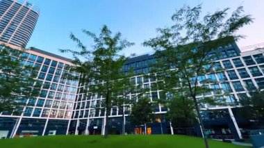 Bratislava, Slovakya - 5 Haziran 2025: Modern tasarımlı şehir parkı. Günbatımında canlı bir şehir parkındaki yeşilliklerle çevrili çağdaş binaların manzarası.