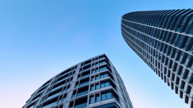 Açık mavi gökyüzü altında modern mimari. Uzun binalar açık mavi gökyüzüne yükseliyor, mimari tasarım ve kentsel yaşam sergileniyor.