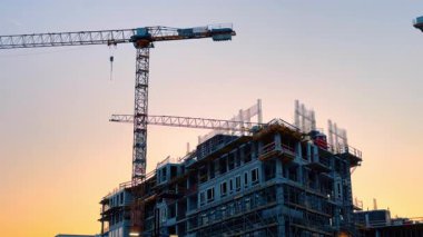 Bratislava, Slovakya - 5 Haziran 2025: Yeni inşaat projesi gün batımında. Arkasında vinçler ve bina yapıları olan renkli bir günbatımına karşı bir inşaat sahası duruyor..