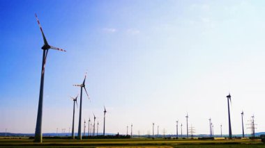 Rüzgar türbinleri temiz enerji üretir. Rüzgar türbinleri, günbatımı saatlerinde açık bir gökyüzüne karşı rüzgar enerjisini kullanan uçsuz bucaksız bir arazide dik dururlar..