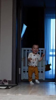 Evinde koşuşturan sevimli mutlu küçük çocuk. Aktif, sağlıklı, beyaz bir çocuk evde oynarken eğleniyor. Düşük açı. Dikey video