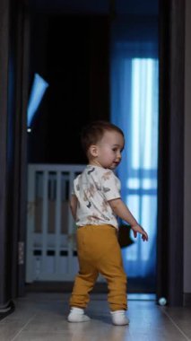 Evin etrafında koşan sağlıklı, aktif, beyaz bir çocuk. Evde oynayan gülümseyen bebek. Dikey video