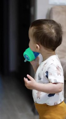 Küçük çocuk odada dikilip şişeden su içiyor. Tatlı çocuk şişeyi düşürür ve kameraya yaklaşır. Dikey video