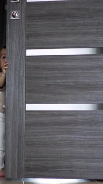Güzel beyaz çocuk evdeki kapıyla oynuyor. Akıllı çocuk kapıyı kapatır ve mutlu bir şekilde gülümser. Dikey video