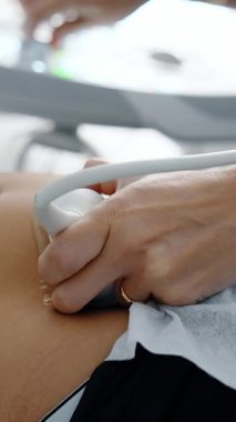 Doktor ultrason makinesindeki sensörü hastanın karnına bastırıyor. Hamileliğin ultrasonik muayenesi. Kapatın. Dikey video