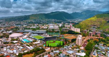Honolulu 'daki Hawaii Üniversitesi' nin stadyumlarına yaklaşıyoruz. Gökyüzünü kaplayan gri, kalın bulutlu dağlar. Hava görünümü.