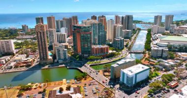 Arabalar Ala Wai Kanalı boyunca Waikiki tatil köyünü belirleyen köprülerden geçiyor. Honolulu 'nun güneşli manzarası, Hawaii, ABD İHA' dan.