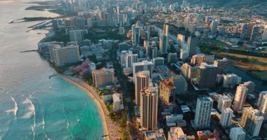 Pasifik Okyanusu dalgaları Waikiki tatil köyünün kumlu plajına doğru ilerliyor. Günbatımında Honolulu, Hawaii, ABD 'de hava perspektifi.