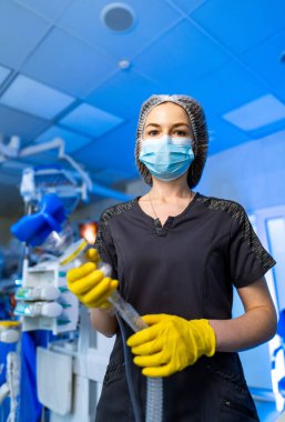 Cerrah ameliyata hazırlanıyor. PPE 'de bir tıp uzmanı bir ameliyathanede hazır bekliyor, yaklaşan prosedürlere ve hasta bakımına odaklanıyor..