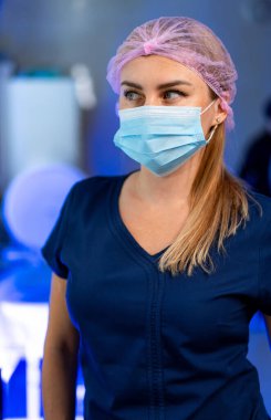 Kendini adamış bir sağlık çalışanı. Maske takan ve şapka takan bir sağlık çalışanı klinik ortama odaklanmış, profesyonellik ve bakım sergiliyor.