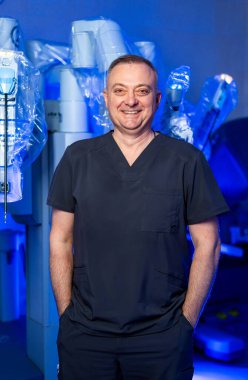 Cerrahi robotlu bir cerrah. Bir tıp uzmanı modern bir ameliyathanede gelişmiş robot cerrahi ekipmanların yanında gururla durur..