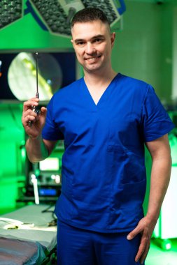 Cerrah parlak bir ameliyat için hazır. Mavi önlüklü bir cerrah, iyi aydınlatılmış bir ameliyathanede güvenle duruyor ve yaklaşan ameliyata hazırlanıyor..