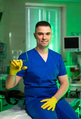 Doktor var mı yok mu? Mavi önlüklü bir tıp uzmanı, parlak ışıklandırılmış bir ameliyathanede ameliyat aletlerini tutarken gülümser..