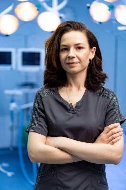 Ameliyathanede kendine güvenen bir cerrah. Kendine güvenen bir cerrah, iyi aydınlatılmış bir ameliyathanede kollarını kavuşturarak profesyonellik ve uzmanlık gösterisi yapar..