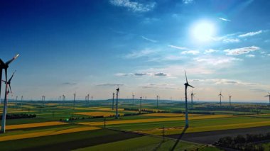 Rüzgar değirmenleri olan güzel yeşil ve sarı tarlalar. Yenilenebilir enerji kavramı. Hava görünümü.