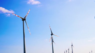 Rüzgar değirmenlerinin tepeleri rüzgarda dönüyor. Sürdürülebilir enerji üretimi. Düşük açı görünümü.