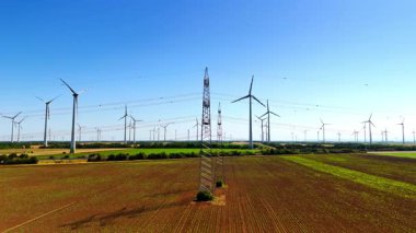 Tarlalarda elektrik hatları ve rüzgar türbinleri var. Kırsal kesimde sürdürülebilir enerji üretimi. Hava görünümü.