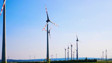 Türbinler temiz enerji üretir. Rüzgar türbinleri, yenilenebilir enerji alanındaki parlak mavi gökyüzüne karşı temiz enerji üretmek için rüzgarı kullanıyor..