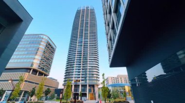 Şehir ortamında modern mimari. Yüksek binalar, yumuşak güneş ışığıyla aydınlık bir günde canlı bir kentsel alanda ufuk çizgisini tanımlar..