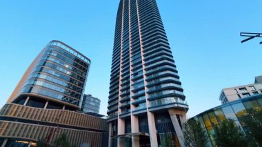 Gökdelen şehrin üzerinde beliriyor. Gün batımında açık mavi gökyüzünün altında çeşitli binalarla çevrili gökdelenler gökdelenlere hakim..