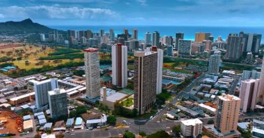 Düşük katlı evlerde birkaç yüksek binaya yaklaşıyoruz. Modern şehir manzarası Honolulu, Hawaii, ABD. Arka planda Waikiki manzarası. Hava görünümü.