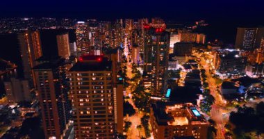 Gökdelenlerin tepesinde kırmızı ışıklar açık bir görüntü. İnsansız hava aracı Waikiki, Honolulu, Hawaii, ABD 'deki aydınlık cadde üzerinde uçuyor..