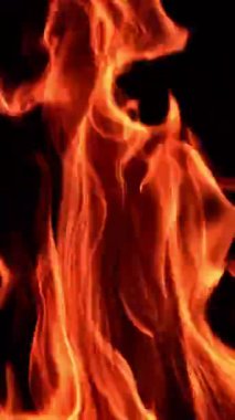 Yanan ateşin güzel kırmızı ve turuncu alevleri. Blaze siyah arka planda izole edildi. Kapatın. Dikey video