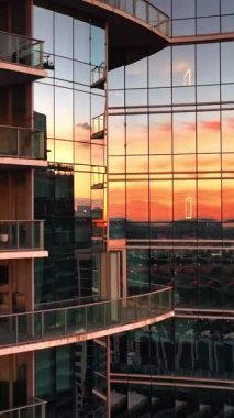 Günbatımının altın ışığı apartmanın ayna pencerelerine yansıyor. Miami, Birleşik Devletler 'deki modern konut binası. Dikey video