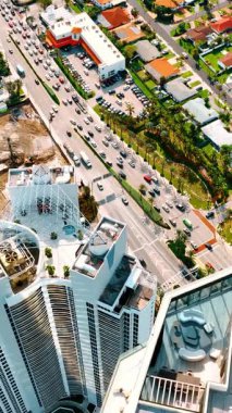 Miami Beach, Florida 'da trafiğin yoğun olduğu otobanın en üst görüntüsü. Güneşli sahil yakınlarında çalışan makineleri olan bir inşaat alanı. Dikey video