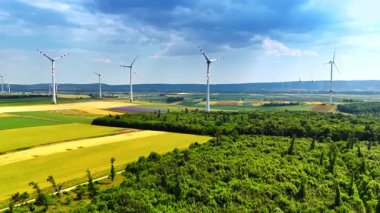 Rüzgar türbinleri temiz enerji üretiyor. Rüzgar türbinleri yemyeşil tarlaların üzerinde kule oluşturarak manzaralı bir kırsal alanda yenilenebilir enerji üretimini sergiliyor..