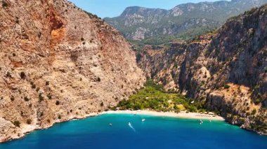 Türkiye 'de sakin bir körfezin manzarası. Sersemletici uçurumlar, berrak bir gökyüzünün altında sakin sularda süzülen teknelerle durgun turkuaz bir körfezin üzerinde yükseliyor..